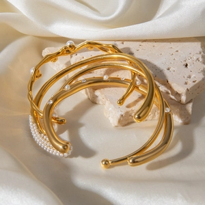 Detail shot of multi-layer gold pearl bracelets on stone with white silk background