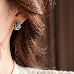 Close-up of vintage 18K gold plated earrings with colorful abalone shell on model ear