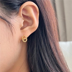 Detail of gold pig nose stud earring with textured beadwork shown on model's ear