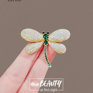Macro shot of dragonfly brooch with gold wings, white diamonds and green gemstones