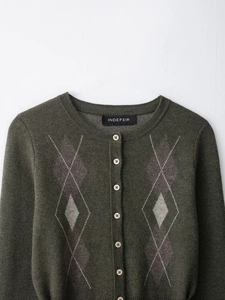 Gros plan détaillé du cardigan en tricot vert foncé à losanges et boutons blancs