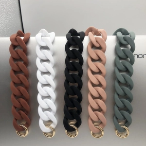 Five colored silicone bag straps with gold metal rings on a sleek silver surface
