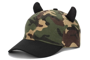Close-up of camouflage baseball cap featuring 3D black devil horns on the top crown