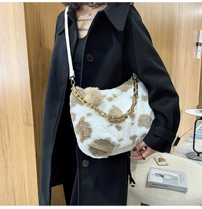 Detail of plush cow print tote bag with thick gold chain and long white shoulder strap
