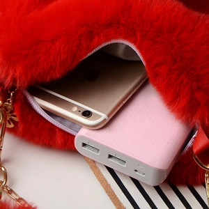 Detail showing the inner capacity of a red heart-shaped plush bag with a smartphone
