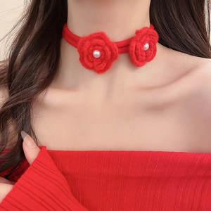 Detail of red knitted flower necklace with white pearls on model for elegant style