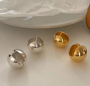 Macro detail of polished spherical hoop earrings in gold and silver finishes