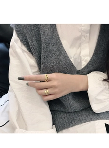 Detailed view of hollow geometric and flat open gold rings on a model's hand