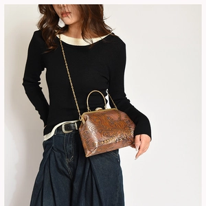 Detail of vintage brown embossed clasp bag with gold chain strap and metal handle