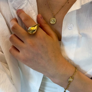 Detail shot of a minimalist gold teardrop ring, coin necklace and stone bracelet