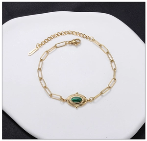 Detailed close-up of a gold stainless steel bracelet with oval green malachite stone