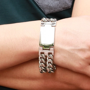 Detail of silver double Cuban chain bracelet with a polished metal plate on a male wrist