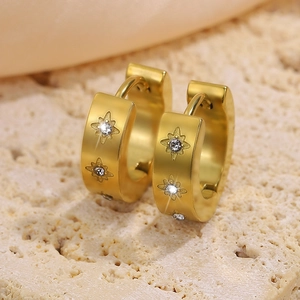 Macro view of gold hoop earrings with star engravings and inlaid white zircon stones