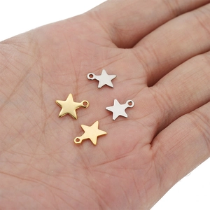 Close-up of small gold and silver star charms on hand for DIY jewelry making size scale