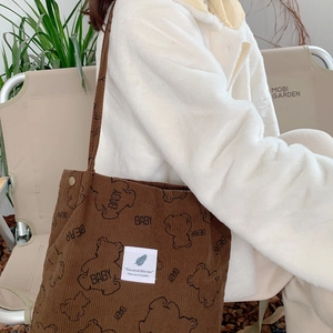 Brown corduroy tote bag with cartoon bear pattern shown in a lifestyle outdoor setting