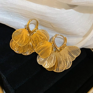 Close-up of gold hollow petal heart-shaped earrings on velvet and silk background