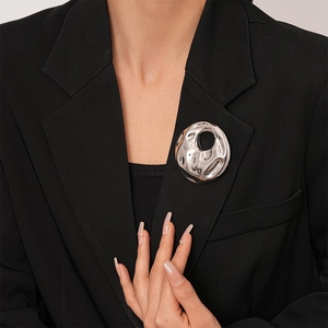 Artistic liquid lava silver brooch with geometric hollow design on a black blazer