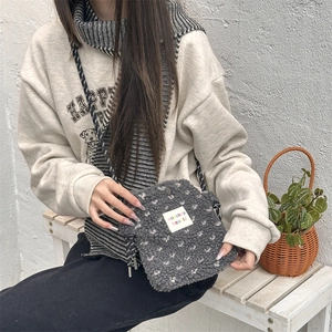Close-up of plush crossbody bag with heart patterns and woven shoulder strap details