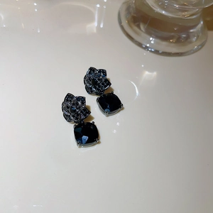 Close-up of black flower drop earrings with cubic zirconia and vintage tassel details