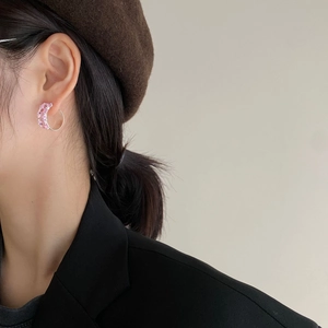 Close-up of S925 silver C-shaped earrings with pink zircon on a model wearing a beret