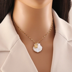 Detail of a gold stainless steel necklace featuring a natural shell and starfish pendant