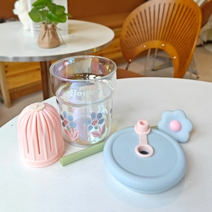Gobelet en verre à fleurs avec étui en silicone rose et paille verte sur la table