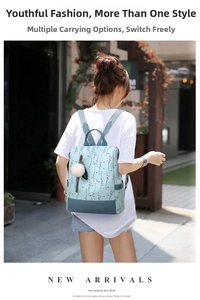 Detail of light blue floral oxford backpack with plush ball charm on a model outdoors