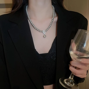 Elegant grey pearl necklace with a teardrop zircon pendant shown on a model in a black suit
