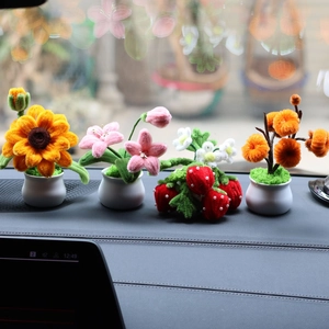 Handmade sunflower and strawberry pipe cleaner plants on a car dashboard display