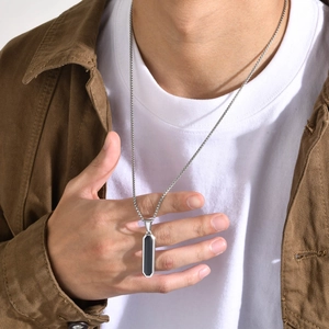 Close-up of minimalist stainless steel necklace with black geometric pendant on male model