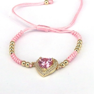 Close-up of pink woven heart bracelet with zircon stones and adjustable gold beads
