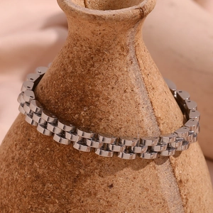 Close-up of a silver stainless steel watch-strap link bracelet on a textured ceramic vase