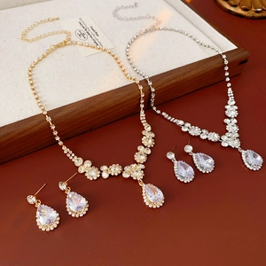 Vue à plat du coffret collier et boucles d'oreilles en zircon doré et argenté sur plateau