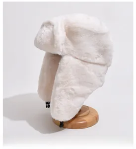 Close-up of plush faux rabbit fur texture and plastic buckle on white winter trapper hat
