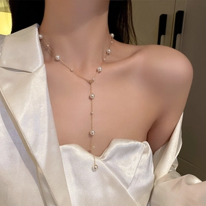 Detail of Y-shaped gold pearl necklace featuring varying sizes and tassel style on model