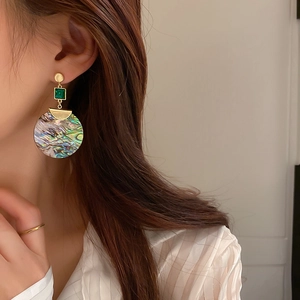 Geometrische goldene Muschelohrringe mit grünem Stein und Abalone-Anhänger am Model