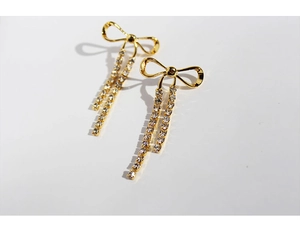 Detailed view of golden bowknot earrings with shimmering rhinestone long tassels