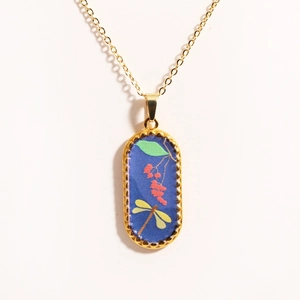 Detailed close-up of 14k gold-filled oval pendant featuring dragonfly and red berries