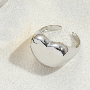 Detailed macro shot of a sleek silver heart-shaped adjustable open ring on a textured surface