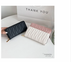 Detail of three PU leather zip wallets showing quilted wavy texture in black, pink and white