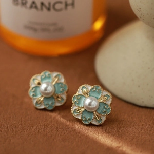 Macro view of blue enamel flower earrings with pearl centers and gold plating