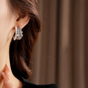 Detail of silver lace earrings with pearls and zircon on model with a vintage aesthetic