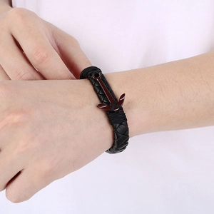 Detail view of woven black leather bracelet with red anchor hook closure for men