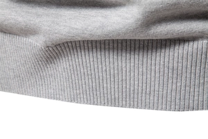 Close-up of high-density light grey knitted ribbed hem and textured sweater fabric