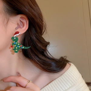 Christmas green dinosaur earrings with red hat and gold ring on female model