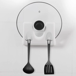 Aan de muur gemonteerd wit plastic pannendekselrek met haken voor keukengerei