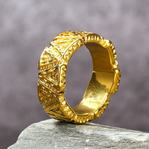 Detailed macro view of gold wide band ring with embossed geometric triangle pattern texture