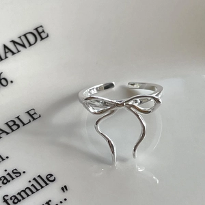 Detail of minimalist 925 sterling silver bow knot open ring on elegant white paper