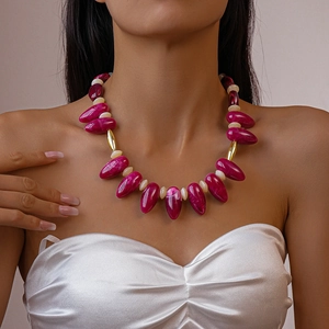 Detailed shot of dark pink resin teardrop beads with golden metal tube accents