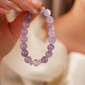Detail of purple amethyst beaded bracelet featuring a faceted clear crystal center stone